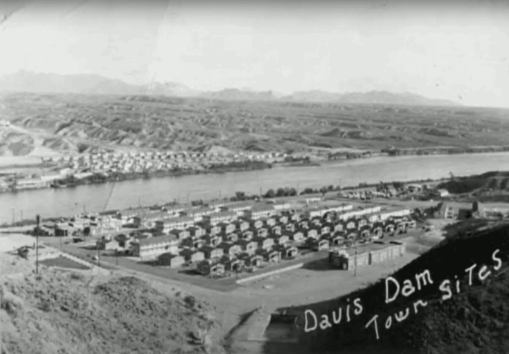 Historic view of Davis Dam Town with river and mountains in background.