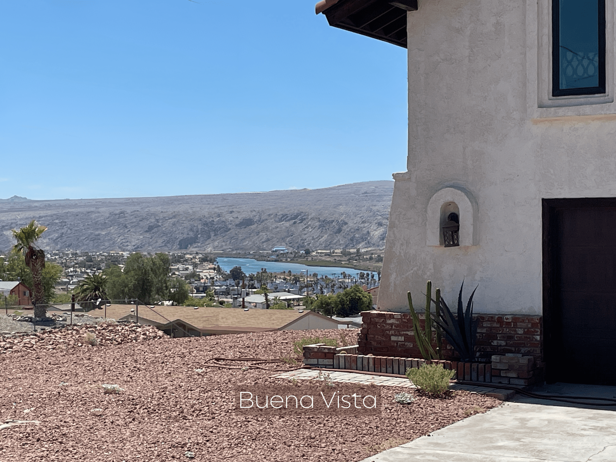 Scenic view of a coastal town with hills and clear blue sky.
