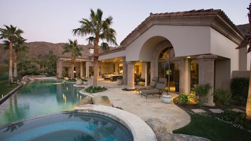 Luxurious house with a pool and palm trees at sunset.